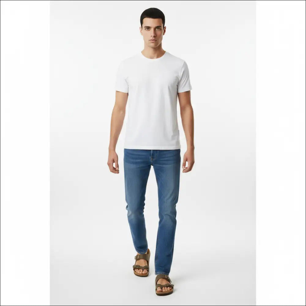 Man wearing Birkenstock Mayari sandals in stone with a white t-shirt and blue jeans.