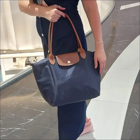 Large Longchamp Tote held by a woman, showcasing the original navy blue design with leather accents.