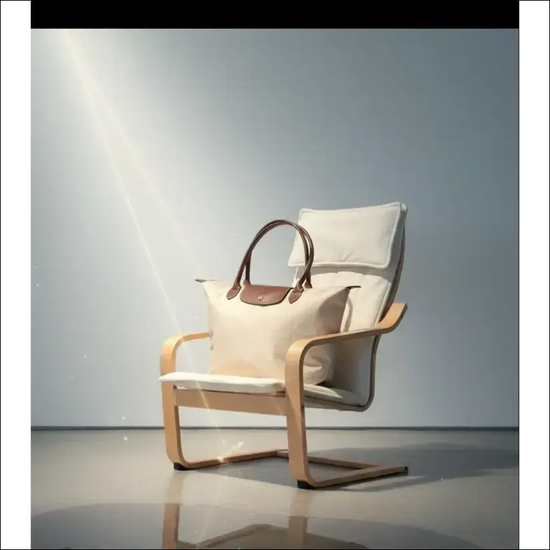 Longchamp Le Pliage L på en stol med en elegant och minimalistisk design i krämvit färg.