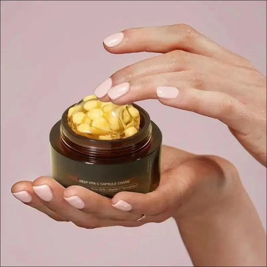 Hands holding a jar of Deep Vita C Capsule Cream, showcasing dermatologically tested Korean skincare.